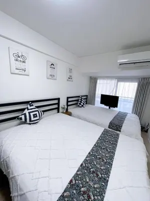 a bedroom with two beds and a tv on the wall at \u65b0\u5bbf\u6700\u4e2d\u5fc3 \u6b4c\u821e\u4f0e\u753a \u4e1c\u65b0\u5bbf4\u5206\u949f \u65b0\u5bbf10\u5206\u949f \u76f4\u8fbe\u6da9\u8c37\u539f\u5bbf \u65b0\u5bbf\u5fa1\u82d1\u5f92\u6b658\u5206\u949f in Tokyo