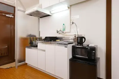 a small kitchen with a microwave and a stove at \u6075\u6bd4\u5bff\u99c5\u304b\u3089\u5f92\u6b691\u5206 \u6e0b\u8c373\u5206 \u65b0\u5bbf10\u5206 30m2\u3067\u3086\u3063\u305f\u308a \u6700\u9ad8\u306e\u7acb\u5730 303\u53f7\u5ba4 in Tokyo