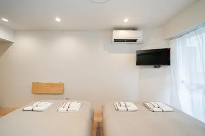 two beds in a room with a tv on the wall at Tokyo Ichiban Kabukicho in Tokyo