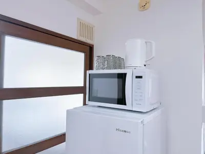 a microwave sitting on top of a refrigerator at Asakusa City Heim in Tokyo