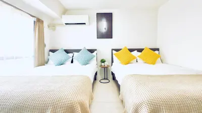 two beds in a room with white and yellow pillows at Asakusa City Heim in Tokyo