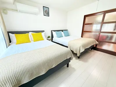 a bedroom with two beds with yellow and blue pillows at Asakusa City Heim in Tokyo
