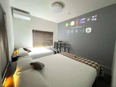 a bedroom with two beds and a wall with pictures on it at Luna House ASAKUSA TOKYO SKYTREE in Tokyo
