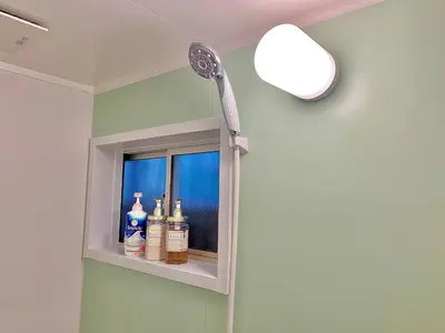 a shower in a bathroom with bottles on a shelf at Luna House ASAKUSA TOKYO SKYTREE in Tokyo