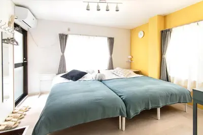 a bedroom with a bed with blue sheets and yellow walls at FIKA Shibuya Honmachi Entire building in Tokyo
