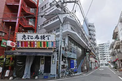 a building with a sign on the side of a street at \u6075\u6bd4\u5bff\u99c5\u304b\u3089\u5f92\u6b691\u5206 \u6e0b\u8c373\u5206 \u65b0\u5bbf10\u5206 30m2\u3067\u3086\u3063\u305f\u308a \u6700\u9ad8\u306e\u7acb\u5730 402\u53f7\u5ba4 in Tokyo