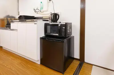 a microwave sitting on top of a refrigerator in a kitchen at \u6075\u6bd4\u5bff\u99c5\u304b\u3089\u5f92\u6b691\u5206 \u6e0b\u8c373\u5206 \u65b0\u5bbf10\u5206 30m2\u3067\u3086\u3063\u305f\u308a \u6700\u9ad8\u306e\u7acb\u5730 403\u53f7\u5ba4 in Tokyo
