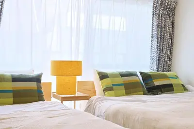 a bedroom with two beds and a lamp and a window at \u6075\u6bd4\u5bff\u99c5\u304b\u3089\u5f92\u6b691\u5206 \u6e0b\u8c373\u5206 \u65b0\u5bbf10\u5206 30m2\u3067\u3086\u3063\u305f\u308a \u6700\u9ad8\u306e\u7acb\u5730 403\u53f7\u5ba4 in Tokyo