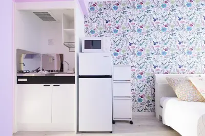 a small bedroom with a bed and a white refrigerator at \u30b9\u30ab\u30a4\u30d5\u30a3\u30fc\u30eb\u5927\u4e45\u4fdd in Tokyo