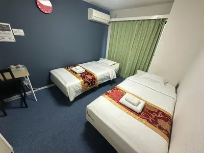 a room with two beds and a table and a clock at Akabane Apart ment Wei hefuyan7190 in Tokyo