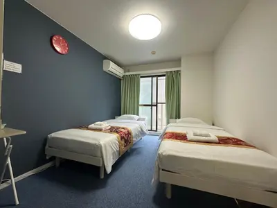 a room with two beds and a clock on the wall at Akabane Apart ment Wei hefuyan7190 in Tokyo