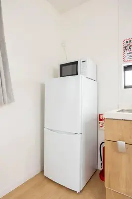 a white refrigerator with a microwave on top of it at \u6771\u5411\u5cf66\u4e01\u76ee in Tokyo