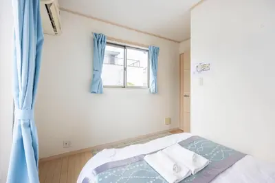 a bedroom with a bed with blue curtains and a window at \u5927\u5cf67\u4e01\u76ee in Tokyo