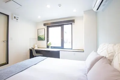a white bedroom with a bed and a window at Minutes from Sumiyoshi & Iconic Attractions & Sky Tree in Tokyo