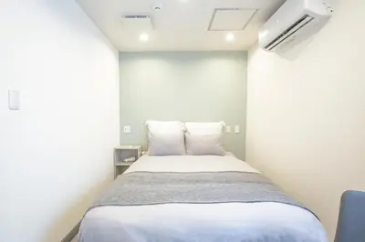 a bedroom with a bed in a white room at Minutes from Sumiyoshi & Iconic Attractions & Sky Tree in Tokyo