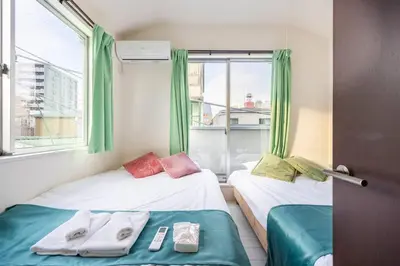 two beds in a room with green curtains and a window at Crown\u6d77\u8fba in Tokyo