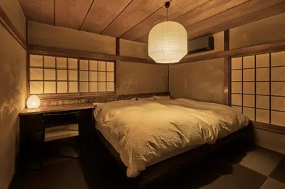 a bedroom with a bed and a desk and a lamp at Rojiura in Tokyo