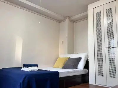 a bedroom with a bed with a blue blanket on it at \u4e09\u30ce\u8f2a \u5409\u539f in Tokyo