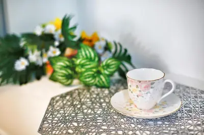 a coffee cup and saucer on a table with flowers at \u30a2\u30ad\u30e9\u5546\u4e8b in Tokyo