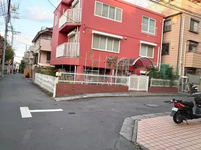 a red building with a scooter parked in front of it at \u30b6\u30b9\u30bf\u30f3\u30c0\u30fc\u30c9\u30a2\u30d1\u30fc\u30c8\u30e1\u30f3\u30c8\u6e0b\u8c37\u7b39\u585ae\u30eb\u30fc\u30e0 in Tokyo