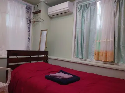 a red bed with a red blanket and a window at \u30b6\u30b9\u30bf\u30f3\u30c0\u30fc\u30c9\u30a2\u30d1\u30fc\u30c8\u30e1\u30f3\u30c8\u6e0b\u8c37\u7b39\u585ae\u30eb\u30fc\u30e0 in Tokyo