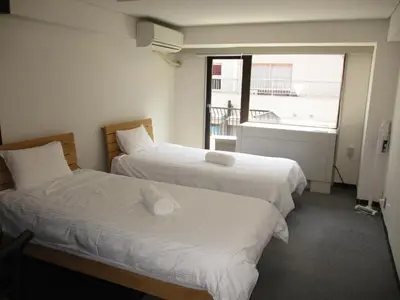 two beds in a hotel room with a window at \u30e9\u30a4\u30aa\u30f3\u30ba\u30de\u30f3\u30b7\u30e7\u30f3\u9053\u7384\u5742\uff42 in Tokyo