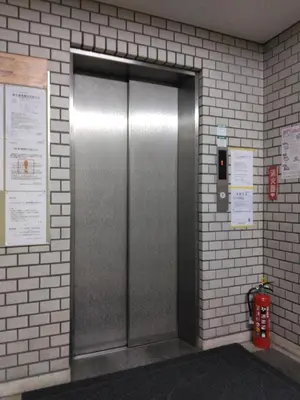 a metal elevator in a brick wall with a fire extinguisher at \u30e9\u30a4\u30aa\u30f3\u30ba\u30de\u30f3\u30b7\u30e7\u30f3\u9053\u7384\u5742\uff42 in Tokyo