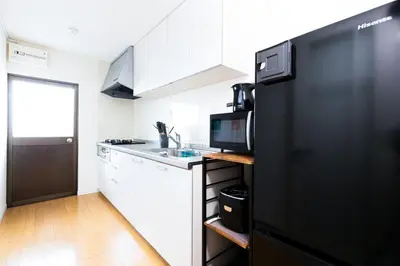 a kitchen with a black refrigerator and white cabinets at Zen Home AKABANE in Tokyo