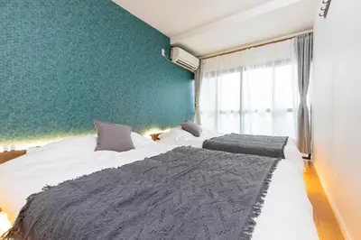 a bedroom with two beds and a green wall at Zen Home AKABANE in Tokyo