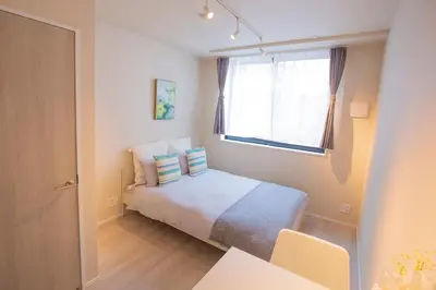 a small bedroom with a bed and a window at Central Yoyogi Guesthouse Y0YG in Tokyo