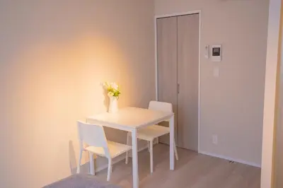 a white table with two chairs and a vase of flowers on it at Central Yoyogi Guesthouse Y0YG in Tokyo