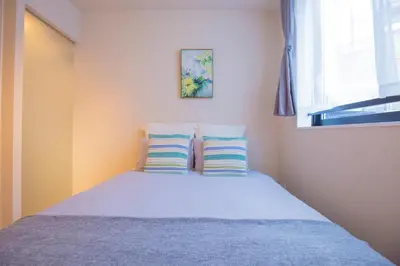 a bedroom with a bed with two pillows and a window at Central Yoyogi Guesthouse Y0YG in Tokyo