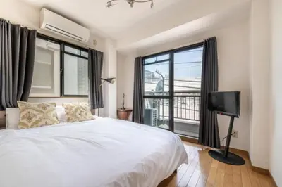 a bedroom with a white bed and a large window at TRILOOP Higashi-Shinjuku in Tokyo