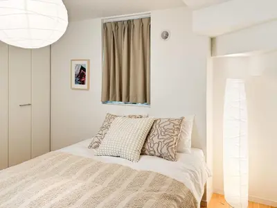 a bedroom with a bed with white sheets and a window at Triphome Shinjuku Takadanobaba Sakura House in Tokyo
