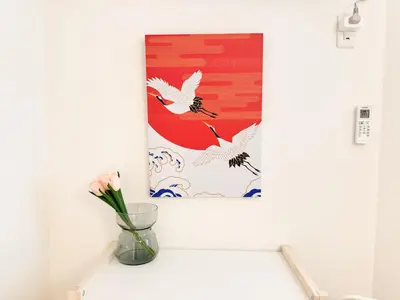 a vase with a flower on a shelf with a painting at Triphome Shinjuku Takadanobaba Sakura House in Tokyo