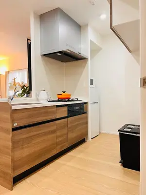 a kitchen with stainless steel appliances and wooden cabinets at Tsubasa Home in Tokyo