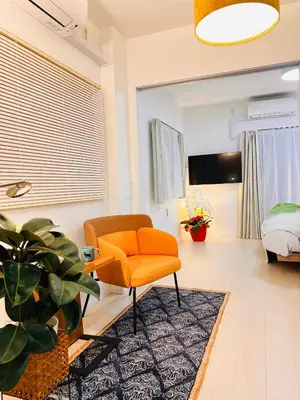 a living room with an orange chair and a rug at Tsubasa Home in Tokyo