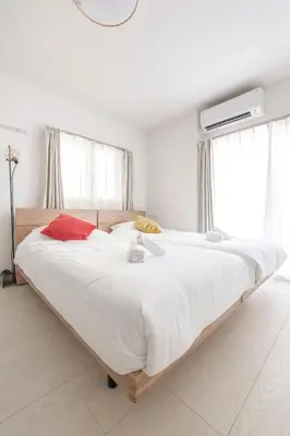 a bedroom with a large bed with white sheets and red pillows at Tsubasa Home in Tokyo