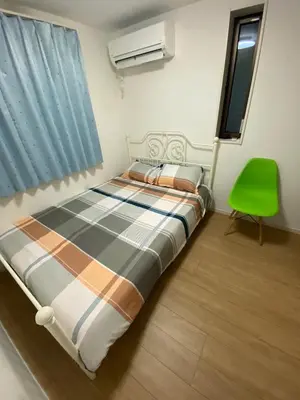 a bedroom with a bed and a green chair at Miaoyi Asakusa in Tokyo