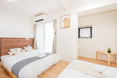 a white bedroom with two beds and a window at New Cozy APT Located on the Japanese Local shopping street in Tokyo