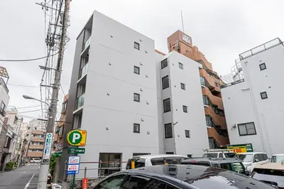a tall white building on a city street with cars at New Cozy APT Located on the Japanese Local shopping street in Tokyo