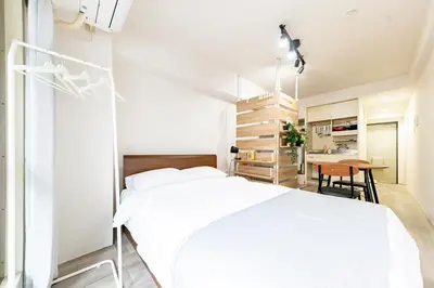 a white bedroom with a white bed and a table at Shinjuku myroom in Tokyo