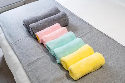 a group of four different colored towels on a bed at Shinjuku myroom in Tokyo