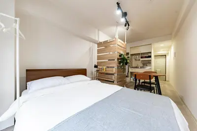 a bedroom with a large white bed and a kitchen at Shinjuku myroom in Tokyo