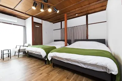 two beds in a room with wooden floors at HOTEL Shibuya Tomigaya in Tokyo
