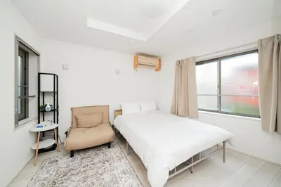 a bedroom with a bed and a chair and a window at Momo-stay Ikebukuro in Tokyo