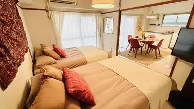 two beds in a room with a table and a kitchen at Shinjuku spacious apartment for max 8ppl in Tokyo