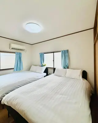 two beds in a room with blue curtains at Holiday Akabane House - A Traditional Japanese House in Tokyo, with Direct Access to Shinjuku & Shibuya in Tokyo