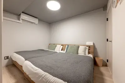 a bedroom with a large bed with green pillows at 24\u5e749\u6708\u30aa\u30fc\u30d7\u30f3 \u767d\u5c71\u99c55\u5206 \u53ce\u5bb912\u4eba \u4e38\u8cb8\u3057\u5207\u308a 101\u5ba4 in Tokyo