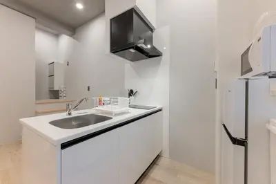 a white kitchen with a sink and a refrigerator at 24\u5e749\u6708\u30aa\u30fc\u30d7\u30f3 \u767d\u5c71\u99c55\u5206 \u53ce\u5bb912\u4eba \u4e38\u8cb8\u3057\u5207\u308a 101\u5ba4 in Tokyo